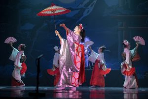 Traditional Japanese performance. Actresses in traditional white and red kimono and fox masks dancing with umbrella and fans.